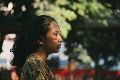 Profile view of woman with face paint against trees