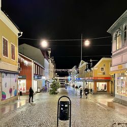 Illuminated street amidst buildings in city at night