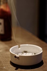 Close-up of cigarette butt in ashtray on table