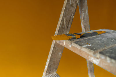 Close-up of metallic structure against yellow orange wall