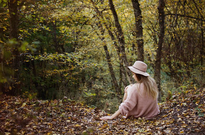 Rear view of woman with autumn leaves in forest