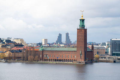 Buildings by river against sky