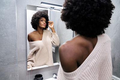 Rear view of shirtless man standing in bathroom