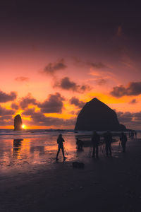 Silhouette people on beach against sky during sunset