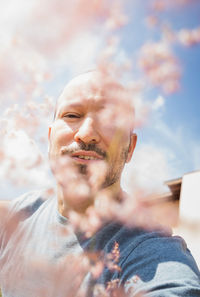 Portrait of man against sky seen through flowers