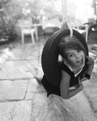 Portrait of girl screaming while swinging on tire