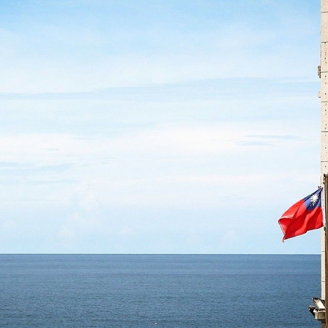 sea, horizon over water, water, sky, tranquil scene, waterfront, tranquility, flag, scenics, beauty in nature, nature, sailboat, patriotism, nautical vessel, rippled, cloud, idyllic, ocean, day, seascape