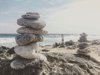 Stack of pebbles on beach against sky