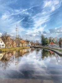 Bridge over river by buildings in city against sky