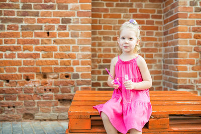 Portrait of cute girl standing against brick wall