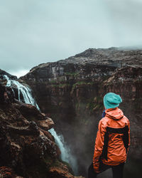 Rear view of hiker looking at waterfall