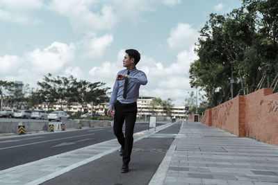 Man standing on road in city against sky