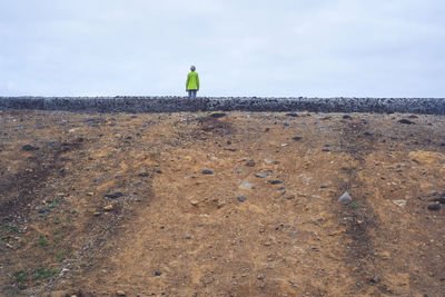 Rear view of woman walking on field against clear sky