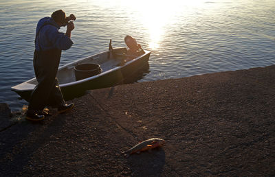 Man sitting on boat in lake during sunset