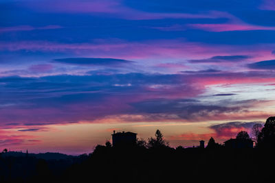 Silhouette trees and buildings against sky at sunset