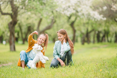 Rear view of women sitting on grass against trees