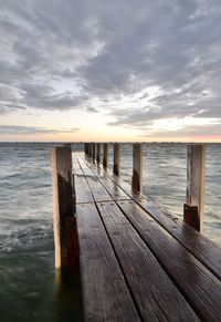 Wooden pier over sea against sky