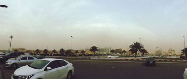 Cars on road against sky in city