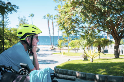 Senior woman wearing helmet sitting at park