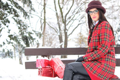 Portrait of young woman wearing hat against trees during winter