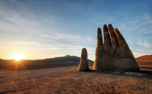 Rocks on field against sky during sunset