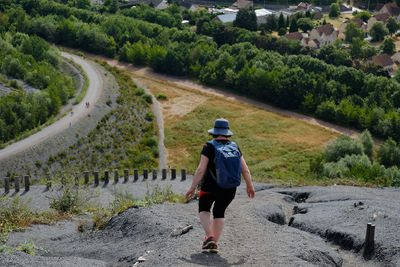 Rear view of woman with backpack walking on rock