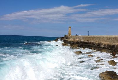 Lighthouse by sea against sky