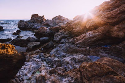 Rocks on seashore against sky