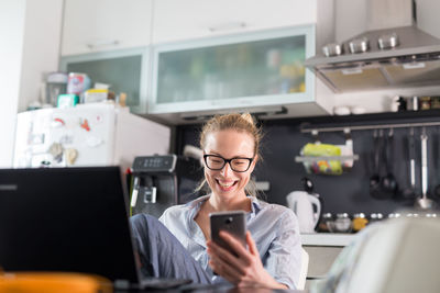 Businesswoman using smart phone sitting at home