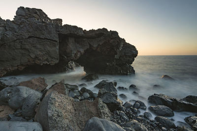 Rocks on sea shore against clear sky