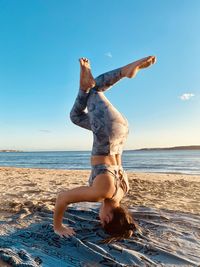 Full length of woman standing at beach against sky