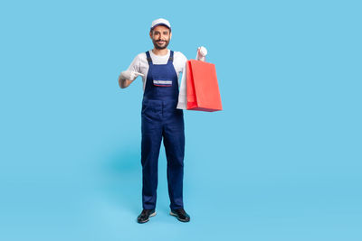 Portrait of smiling man standing against blue background