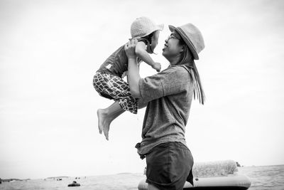 Rear view of mother and daughter against sea against sky