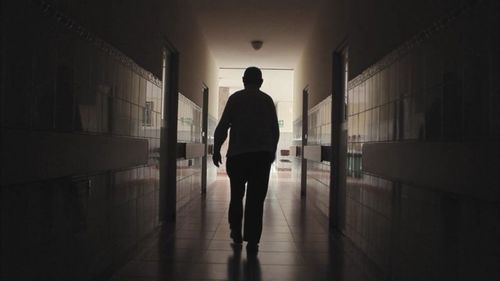 Rear view of man walking in corridor of building