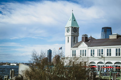Clock tower amidst buildings in city against sky