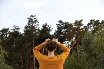 Rear view of woman standing by plants against sky