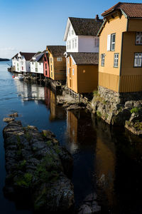 Buildings by river against sky