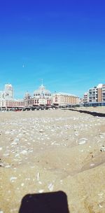 Scenic view of beach against clear blue sky in city