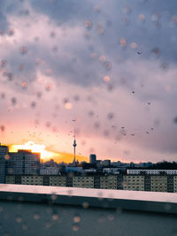 Cityscape against cloudy sky during sunset with raindrops 