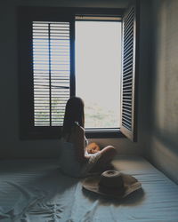 Young woman sitting by window at home