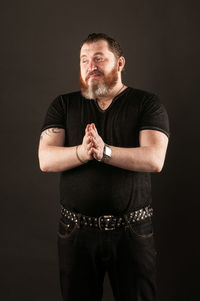 Portrait of senior man standing against black background