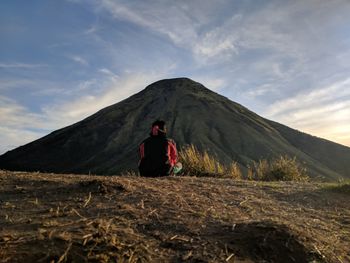 Rear view of man on arid landscape against sky