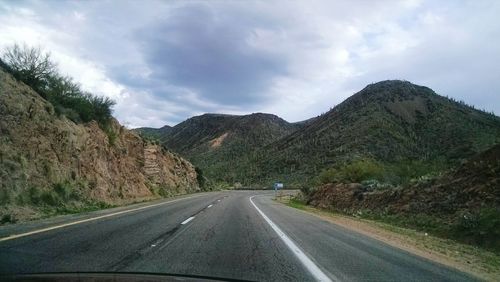 Road by mountains against sky