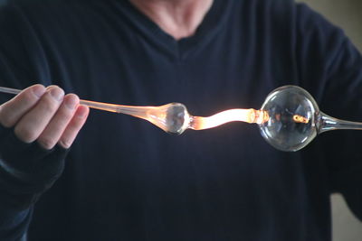 Midsection of man shaping heated glass