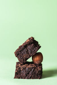 Stack of two dark chocolate brownies and a hazelnut, on a mint green background. chocolate cake.