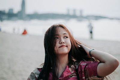 Portrait of beautiful young woman against blurred background