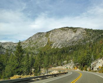 Road by trees against sky