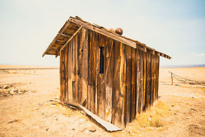 Wooden hut on beach against sky