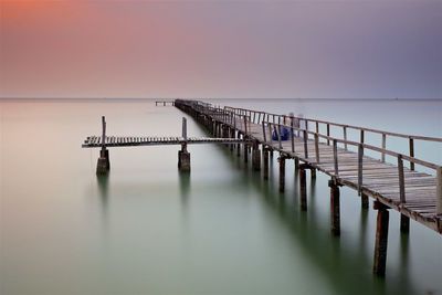 Pier over sea against clear sky during sunset