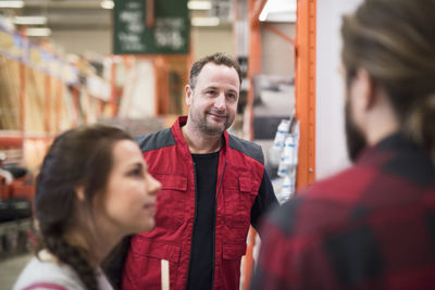 Smiling salesman looking at couple in hardware store